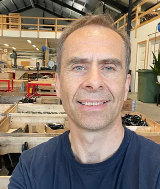 Mann tar selfie innendørs i moderne bygg med fargerik og lys kunstinstallasjon i bakgrunnen.